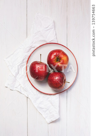 Three red ripe apples on a plate. Top view on a wooden table. Three red ripe apples on a plate. Top view on a wooden table. 139754663