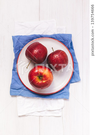 Three ripe red apples on a white plate. Top view. Three ripe red apples on a white plate. Top view. 139754666
