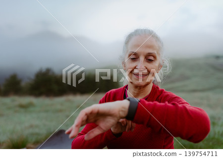 Senior woman checking her performance after run in nature on early morning. 139754711