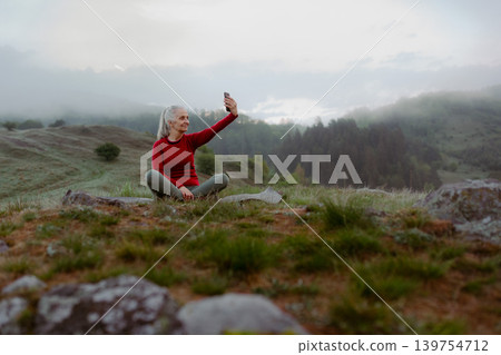 Senior woman taking selfie after yoga session in morning nature. Senior woman taking selfie after yoga session in morning nature. 139754712