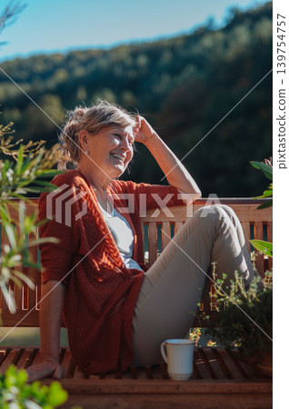 Mature woman having morning coffee on cozy cabin balcony. 139754757