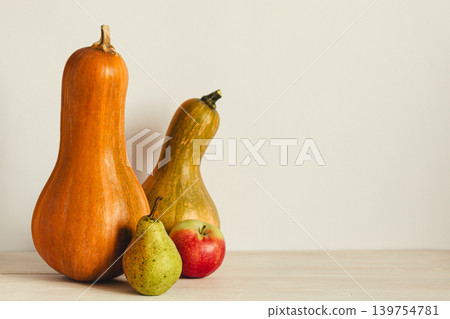 Two ripe organic pumpkin, pear and apple on a pastel beige background. Minimal eco concept for Thanksgiving card or background. Two ripe organic pumpkin, pear and apple on a pastel beige background. Minimal eco concept for Thanksgiving card or background. 139754781