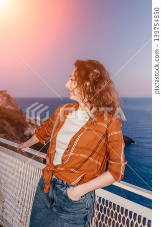 Woman sunset coast young woman enjoying the peaceful mediterranean breeze while standing on a balcony at golden hour 139754850