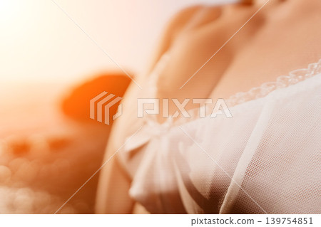 Lingerie sunset beach close up of woman wearing delicate white lace during golden hour for romantic summer vacation and relaxation Lingerie sunset beach close up of woman wearing delicate white lace during golden hour for romantic summer vacation and relaxation 139754851