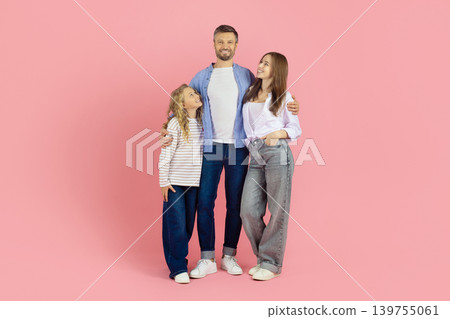 Happy family of three standing together on pink background, looking at father Happy family of three standing together on pink background, looking at father 139755061
