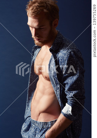 Fashion, thinking or model with abs in studio on a blue background wearing an open unbuttoned shirt. Ginger man, body or handsome male person posing on color wall for masculine style with six pack Fashion, thinking or model with abs in studio on a blue background wearing an open unbuttoned shirt. Ginger man, body or handsome male person posing on color wall for masculine style with six pack 139755269