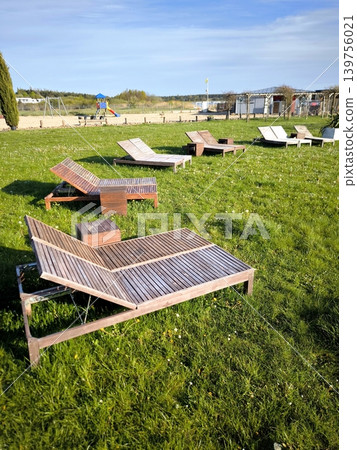 Wooden sun loungers for relaxing on a green lawn Wooden sun loungers for relaxing on a green lawn 139756021