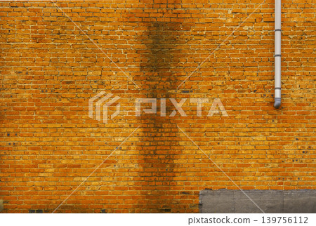 Rustic suburban structure with vertical strength. Weathered orange brick with moss at foundation line Rustic suburban structure with vertical strength. Weathered orange brick with moss at foundation line 139756112