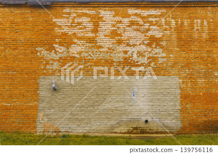 Worn brick with peeling paint. Faded orange brick surface showing signs of neglect and deterioration Worn brick with peeling paint. Faded orange brick surface showing signs of neglect and deterioration 139756116