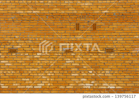 Sunlit vintage brick wall showcasing vents and aged charm perfect for photography and restoration ideas 139756117