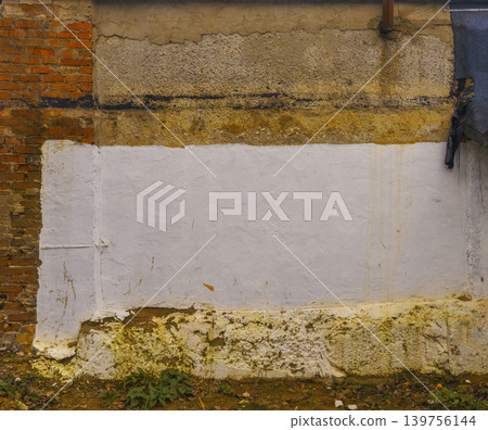 Macro photograph of aged plaster and brick seam highlighting moss and textured paint features 139756144