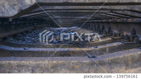 Detailed view of corroded railway elements with ballast and fasteners in moody urban setting Detailed view of corroded railway elements with ballast and fasteners in moody urban setting 139756161