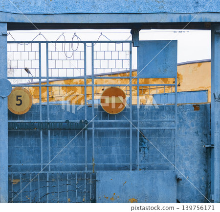 Closed industrial gate with warning signs. Metal gate preventing entry with warning signs present Closed industrial gate with warning signs. Metal gate preventing entry with warning signs present 139756171