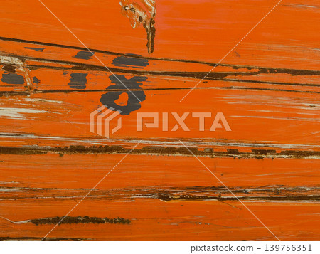Macro texture of weathered orange paint on a wooden surface. Abstract background with deep cracks, scratches, and visible wood grain through peeling paint layers. Wooden fence or flooring. Macro texture of weathered orange paint on a wooden surface. Abstract background with deep cracks, scratches, and visible wood grain through peeling paint layers. Wooden fence or flooring. 139756351