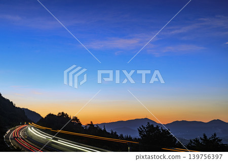A highway at dawn in a mountain village where morning mist flows. A highway at dawn in a mountain village where morning mist flows. 139756397
