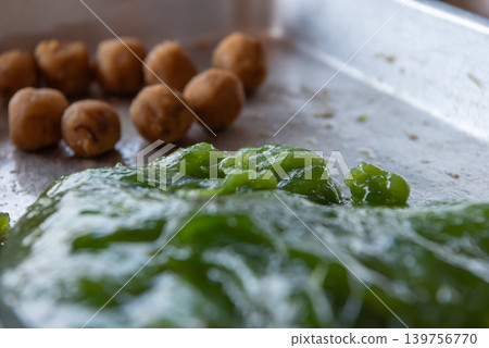 Green Kanom Tian dough sweet filling balls prepared for making traditional Thai dessert during festive cooking process Green Kanom Tian dough sweet filling balls prepared for making traditional Thai dessert during festive cooking process 139756770