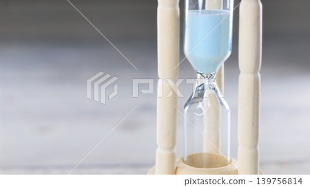 A blue hourglass placed on a wooden table A blue hourglass placed on a wooden table 139756814