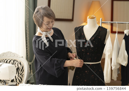 資深女設計師在她們的工作室裡製作服裝。 資深女設計師在她們的工作室裡製作服裝。 139756844