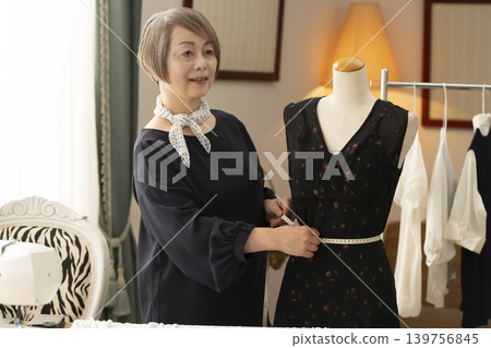 資深女設計師在她們的工作室裡製作服裝。 資深女設計師在她們的工作室裡製作服裝。 139756845