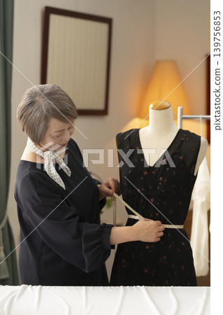 資深女設計師在她們的工作室裡製作服裝。 資深女設計師在她們的工作室裡製作服裝。 139756853