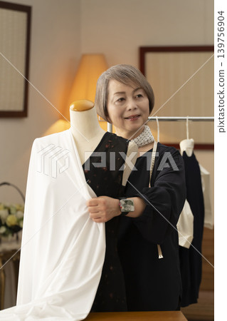資深女設計師在她們的工作室裡製作服裝。 資深女設計師在她們的工作室裡製作服裝。 139756904