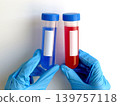 Gloved hands holding laboratory sample tubes for infectious disease testing and medical analysis. Healthcare concept for virus diagnostics, biological research and scientific studies. 139757118