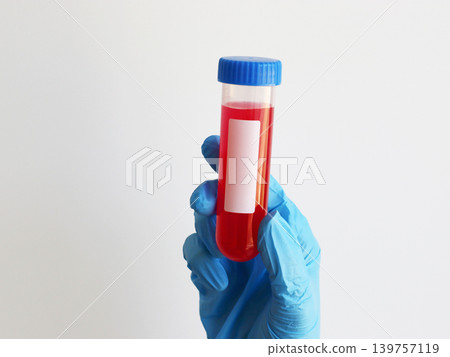 Gloved hand holding laboratory test tube with red liquid for virus testing and infectious disease diagnostics. Healthcare concept for medical research, sample analysis and pathogen detection. Gloved hand holding laboratory test tube with red liquid for virus testing and infectious disease diagnostics. Healthcare concept for medical research, sample analysis and pathogen detection. 139757119