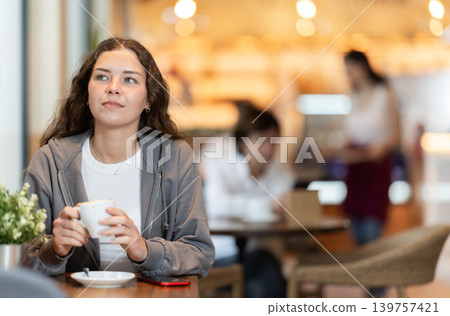 Girl whiles away time and waits for meeting in chain cafe Girl whiles away time and waits for meeting in chain cafe 139757421