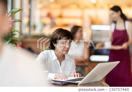 Elderly woman with laptop in cafe Elderly woman with laptop in cafe 139757460