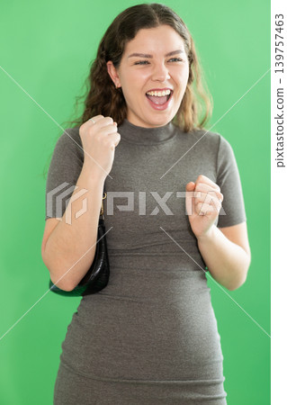 Portrait of girl expressing happy emotions on green background 139757463