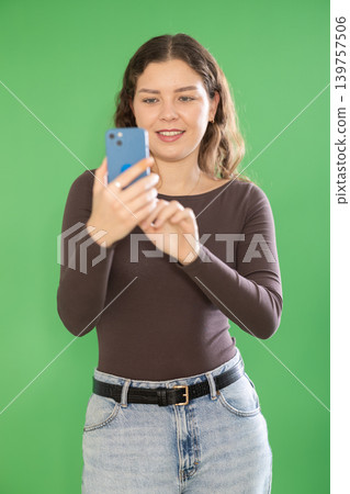 Young woman taking photo or scanning QR code in front of green screen Young woman taking photo or scanning QR code in front of green screen 139757506