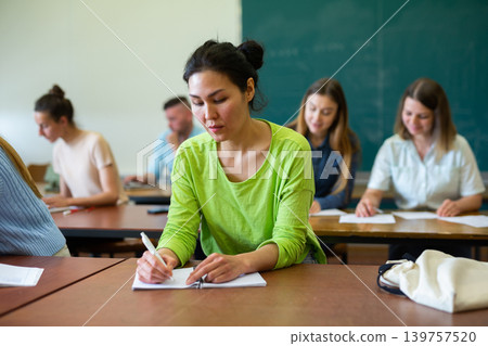 Woman university student writing in classroom Woman university student writing in classroom 139757520