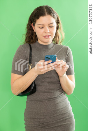 Young woman scrolling smartphone screen in front of green screen Young woman scrolling smartphone screen in front of green screen 139757538