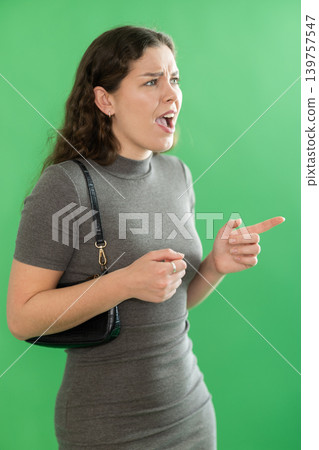Young woman angry and yelling in front of green screen Young woman angry and yelling in front of green screen 139757547