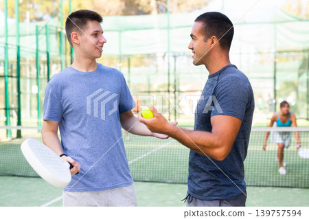 Men chatting on outdoor padel tennis court 139757594