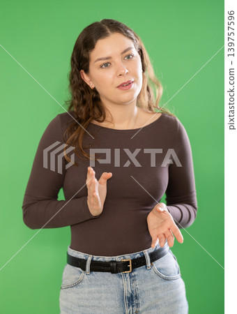 Young woman talking in front of green screen 139757596
