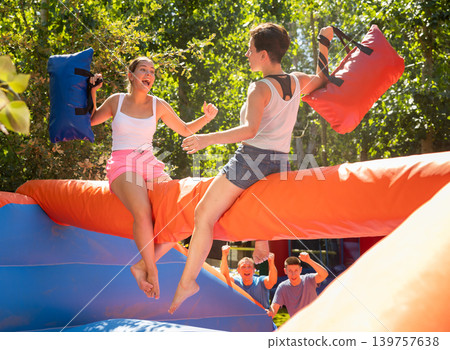 Women holding soft pillows and fighting in adventure park Women holding soft pillows and fighting in adventure park 139757638