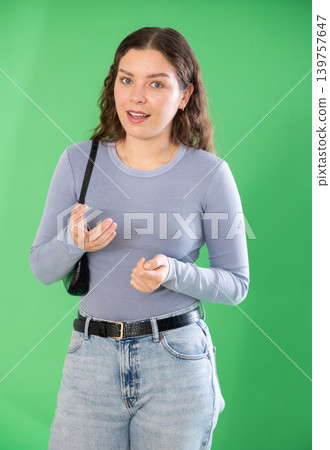 Young woman talking in front of green screen 139757647