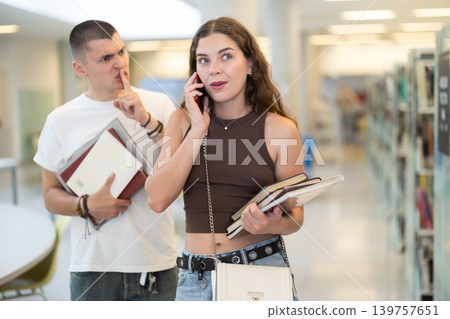Male student makes remark to woman talking on phone in library Male student makes remark to woman talking on phone in library 139757651