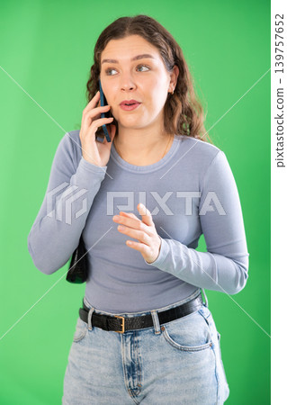 Young woman talking on mobile phone in front of green screen Young woman talking on mobile phone in front of green screen 139757652
