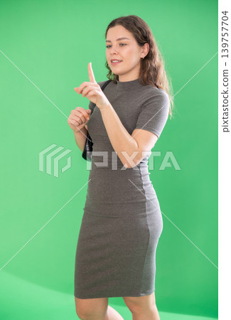 Pretty girl taps her finger on virtual screen in front of her. Chroma key compositing 139757704