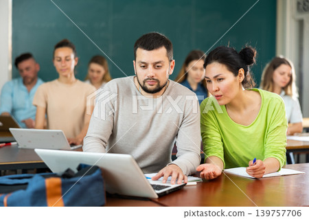 Woman and man university students using laptop and exercising together Woman and man university students using laptop and exercising together 139757706