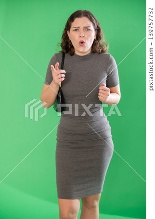 Young woman angry and yelling in front of green screen 139757732