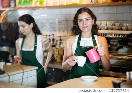 Girl cafe worker pours coffee from cezve coffee pot into cup Girl cafe worker pours coffee from cezve coffee pot into cup 139757754