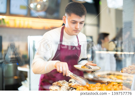 Guy salesperson and girl works in cafeteria bakery shop Guy salesperson and girl works in cafeteria bakery shop 139757776