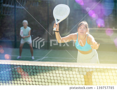 Sporty young woman playing padel on open court on summer Sporty young woman playing padel on open court on summer 139757785