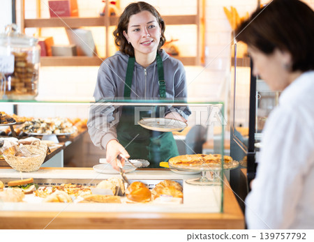 Young woman giving pastry to client in cafe Young woman giving pastry to client in cafe 139757792