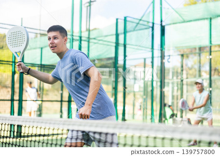 Young man playing padel tennis on court Young man playing padel tennis on court 139757800