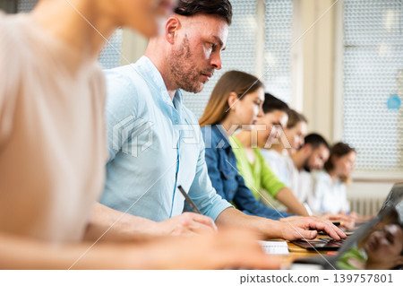 Portrait of a student guy, studying on a laptop and writing a synopsis Portrait of a student guy, studying on a laptop and writing a synopsis 139757801
