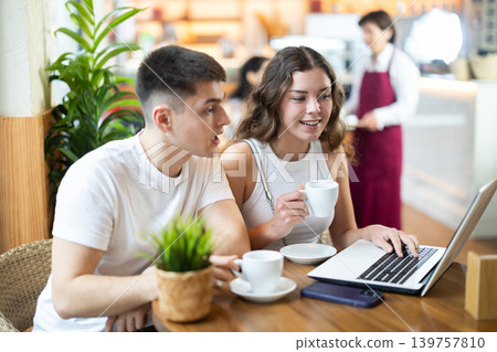 Couple man and woman with laptop drinking coffee and talking Couple man and woman with laptop drinking coffee and talking 139757810